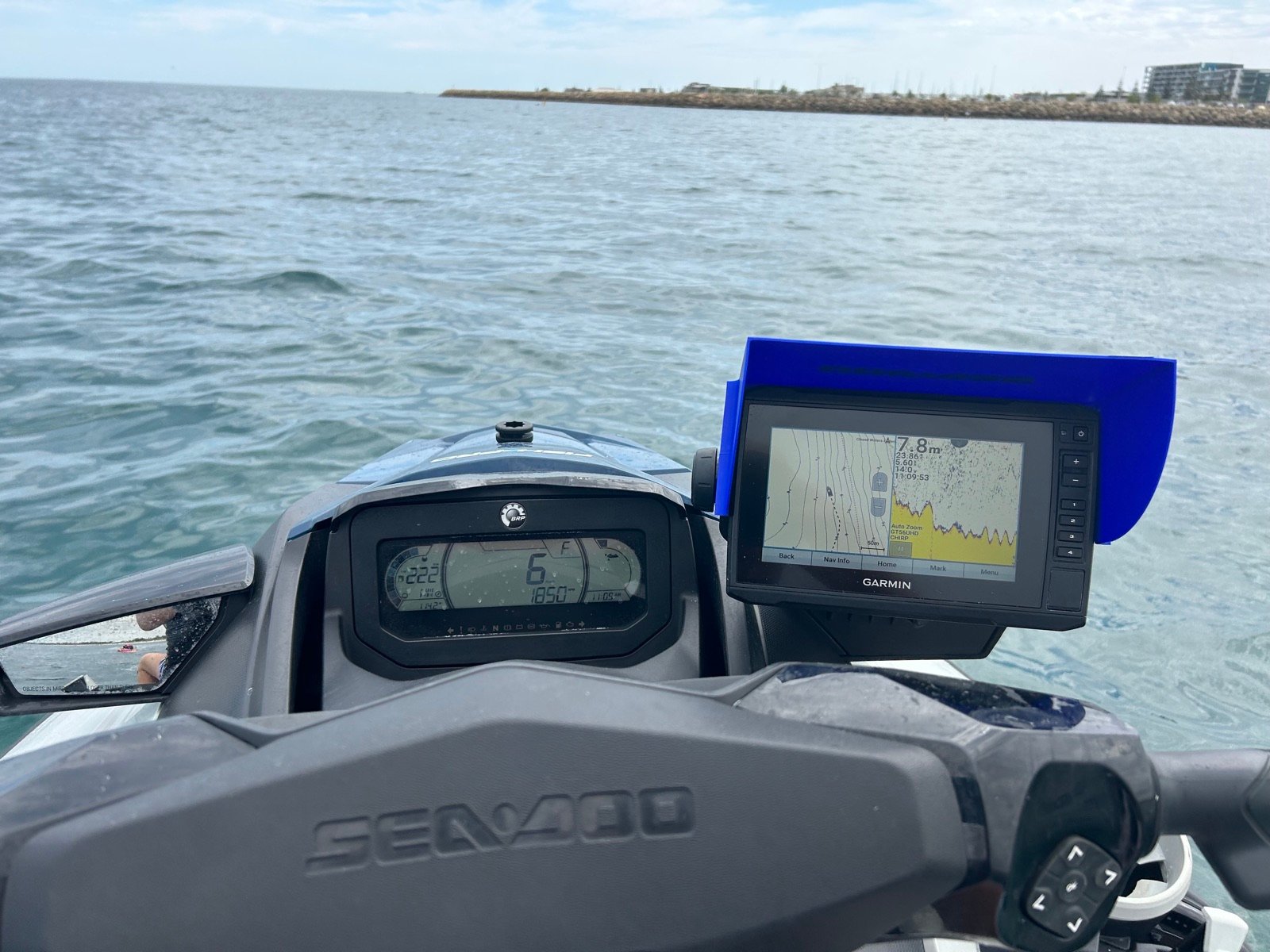 Garmin fish finder with blue JetSkiVisor sun shield mounted on a Sea-Doo, screen clearly readable on the water